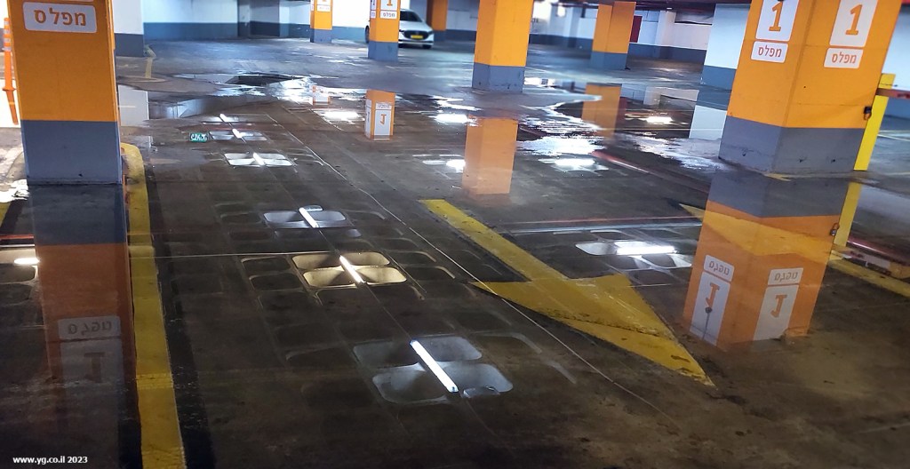השתקפות. שכבה עדינה של מים בחניון גרמה לרצפת הבטון לשקף את התקרה שמעליה