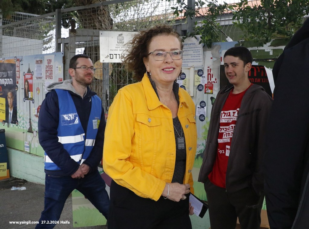 
הבחירות לרשויות המקומיות - חיפה 27.2.2024 - ראש העיר עינת קליש בדרך עברה לקלפי ליד נציגים של המועמדת לראשות העיר עו"ד שרית גולן (באדום) והמועמד לראשות העיר דוד עציוני (בכחול)
