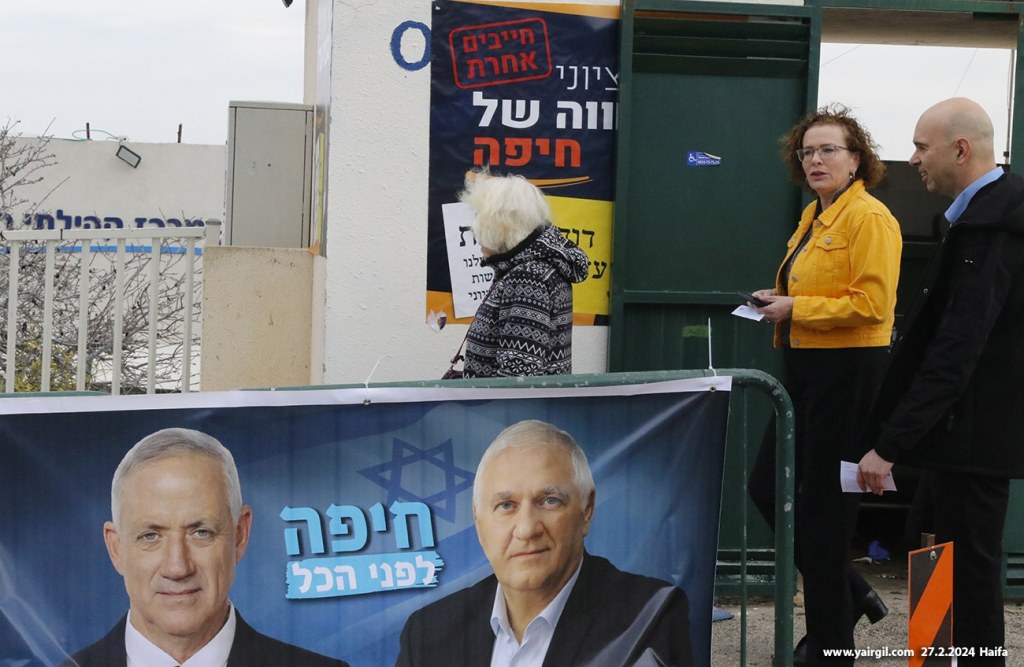 הבחירות לרשויות המקומיות - חיפה 27.2.2024 - ראש העיר עינת קליש בדרך לקלפי בין פרסומות של מועמדים אחרים